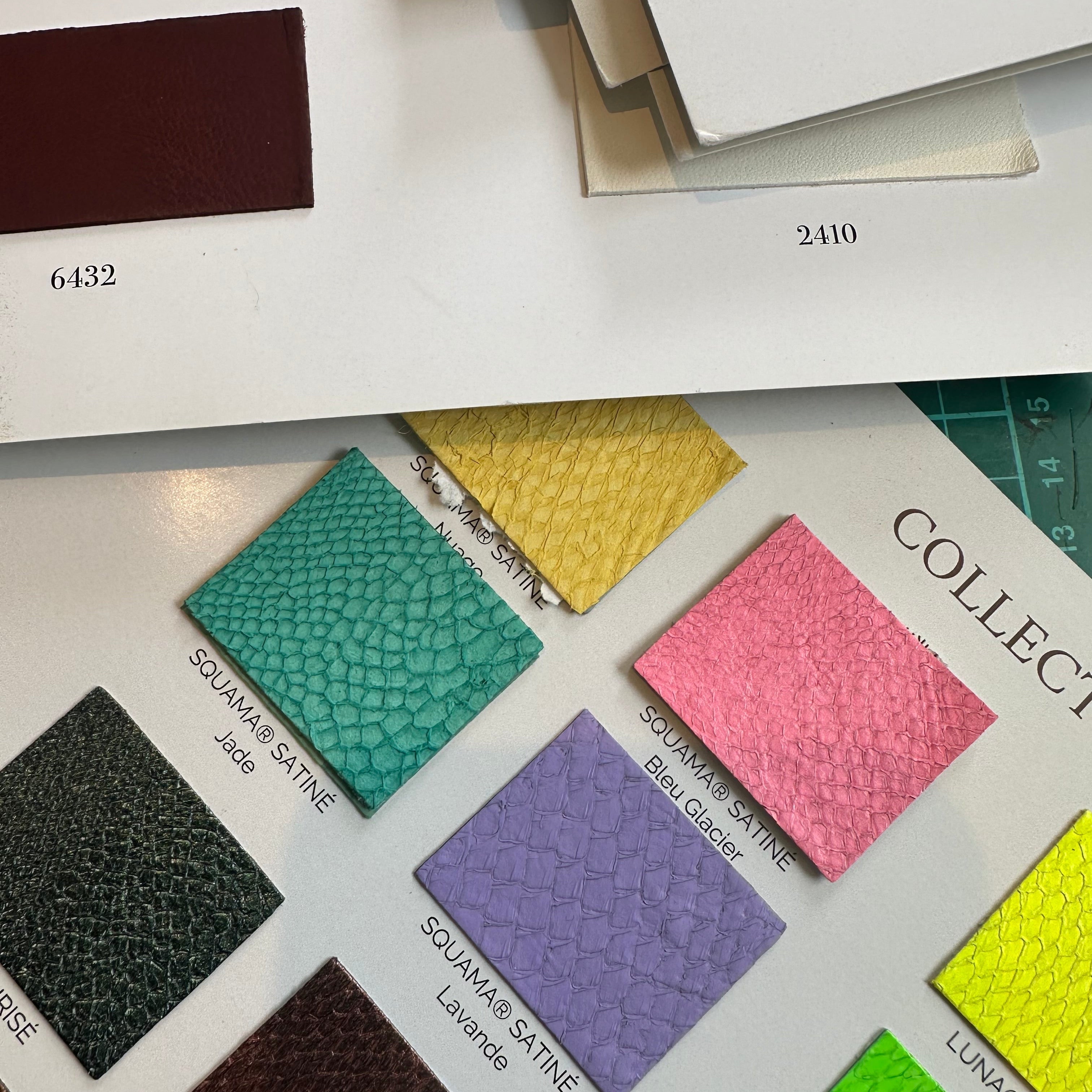 Elandetta ‘Colour Confidence’ journal page showing a printed sheet with Souama® satine colour swatches in shades of jade, yellow, pink, purple and green, alongside numbered leather samples, illustrating the brand’s colour‑led design philosophy.