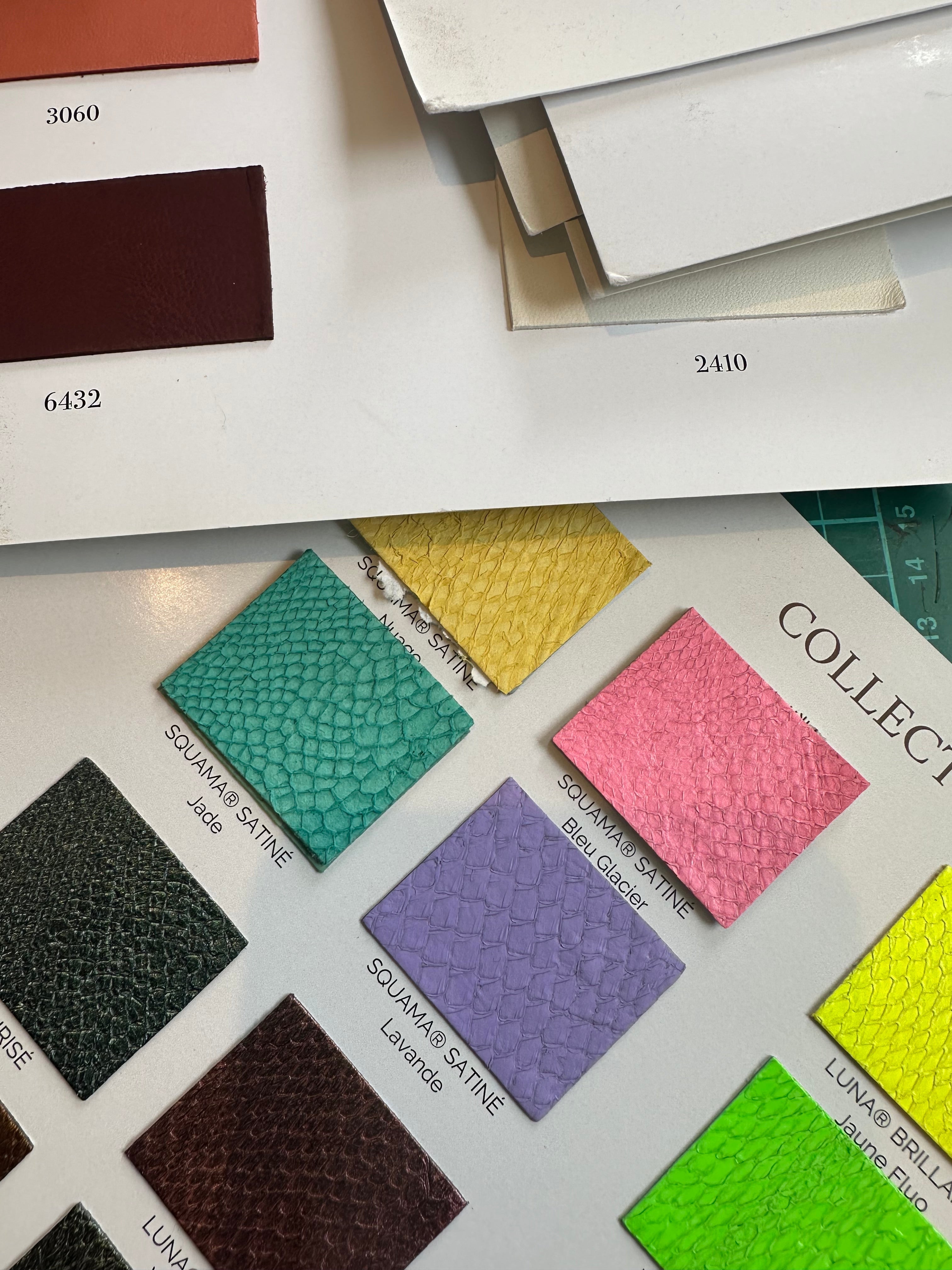 Elandetta ‘Colour Confidence’ journal page showing a printed sheet with Souama® satine colour swatches in shades of jade, yellow, pink, purple and green, alongside numbered leather samples, illustrating the brand’s colour‑led design philosophy.