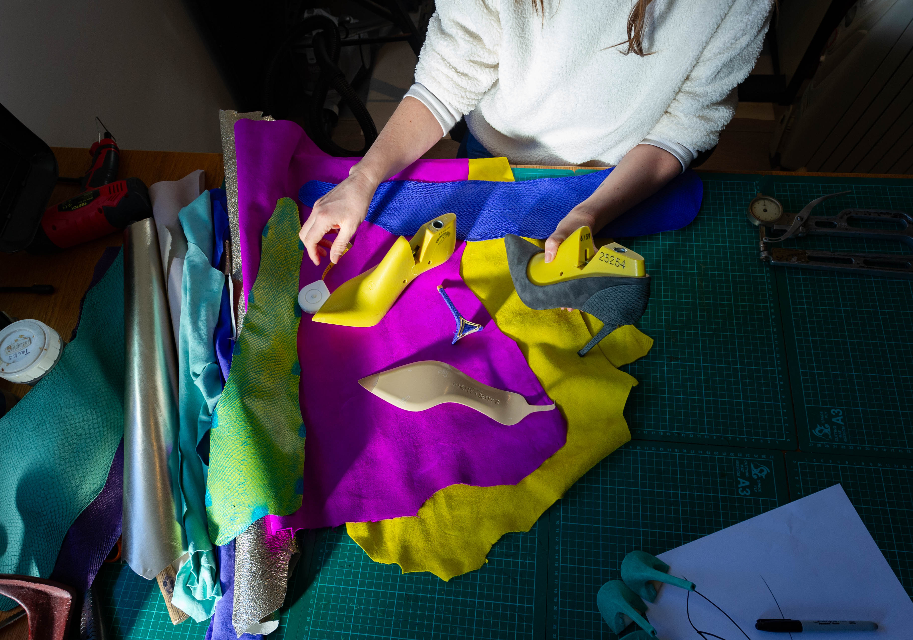 British shoemaker Hetty Rose working with Elandetta shoe lasts, heel components and vibrant leather swatches in electric blue, yellow and pink during the development of Elandetta luxury pointed heels. The image reflects Elandetta’s focus on craftsmanship, colour confidence and thoughtful footwear design.