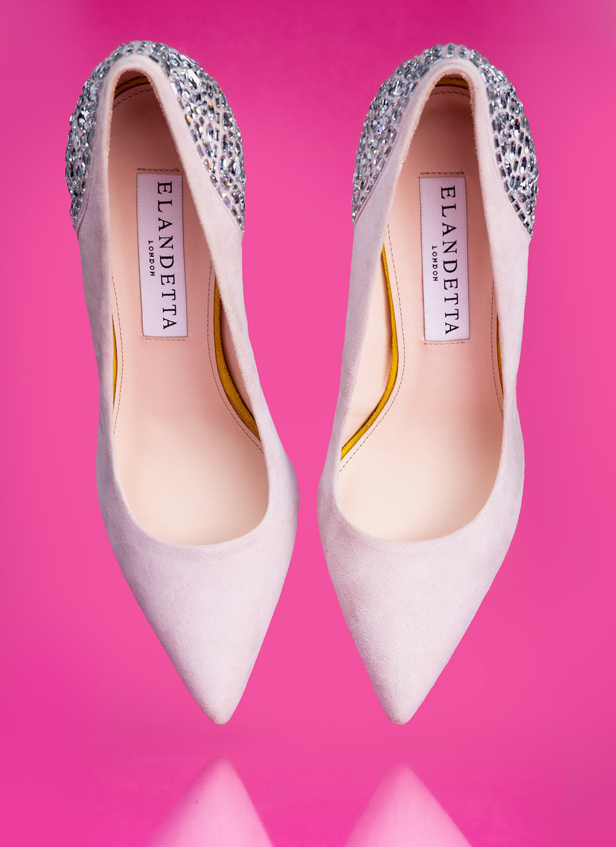 Elandetta Heather luxury pointed heels in soft pink suede with hand-encrusted crystal embellishment, photographed against a bold pink backdrop to showcase colour confidence, craftsmanship and statement British footwear design.