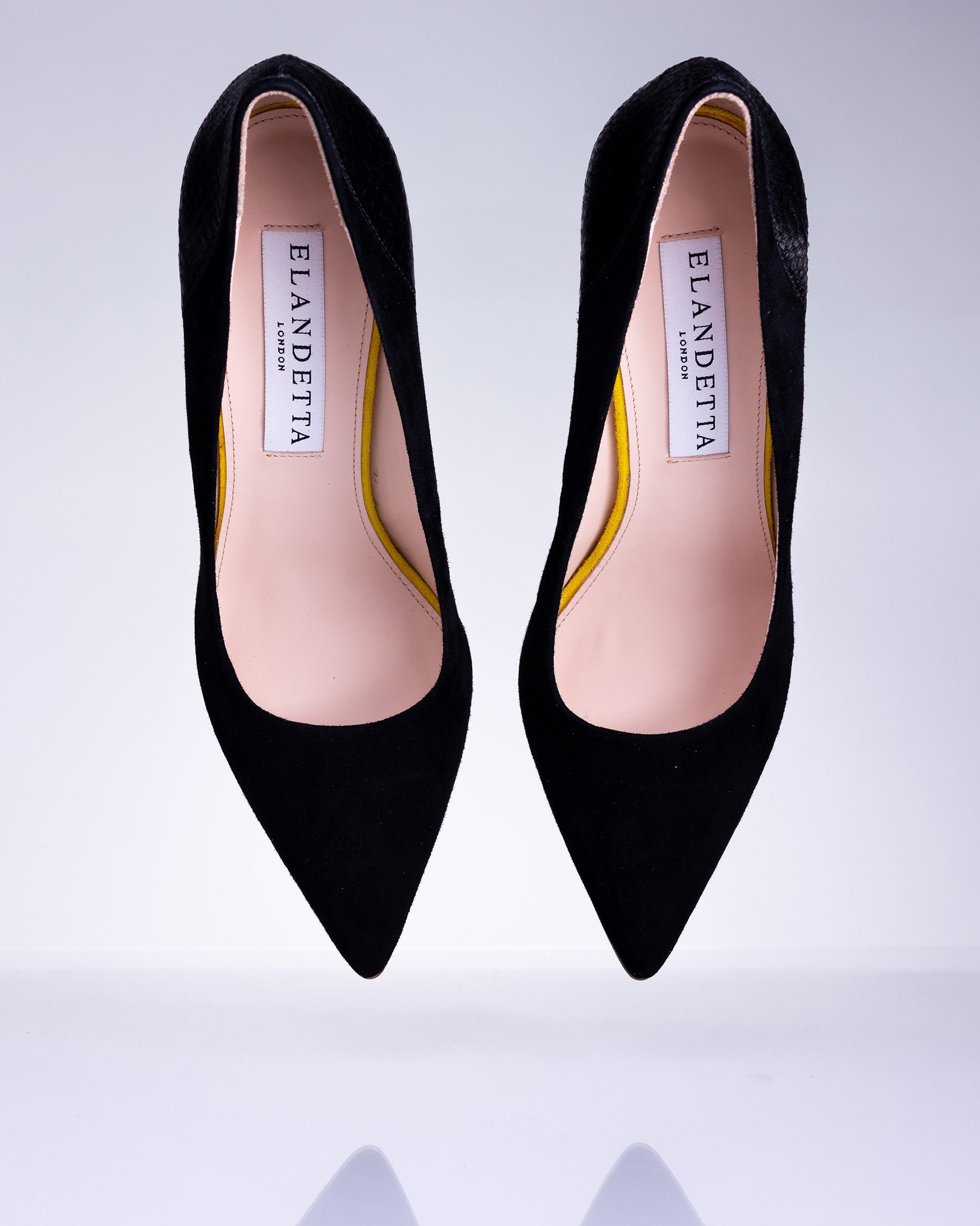 Pair of Elandetta Ink deep black suede pointed heels with textured black leather detailing and elegant silhouette.