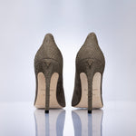 A pair of women's pointed-toe stiletto pumps shown from the back, featuring a taupe suede leather, with a light beige insole and black heels, set against a clean white background.