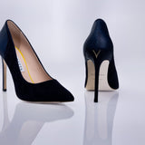 A pair of pointed-toe high heels in dark navy blue textured suede leather, shown from both the side and back angles on a reflective white surface.